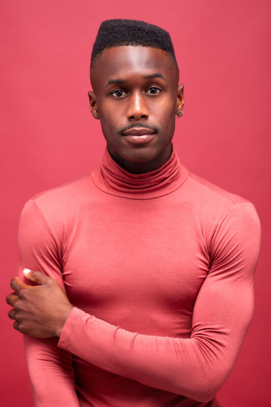 Marcus Zebra, a New York City Dancer. A portrait of him in a pink roll neck against a pink background